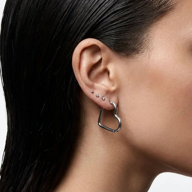 Close-up of an ear wearing a silver hoop earring with a blurred background