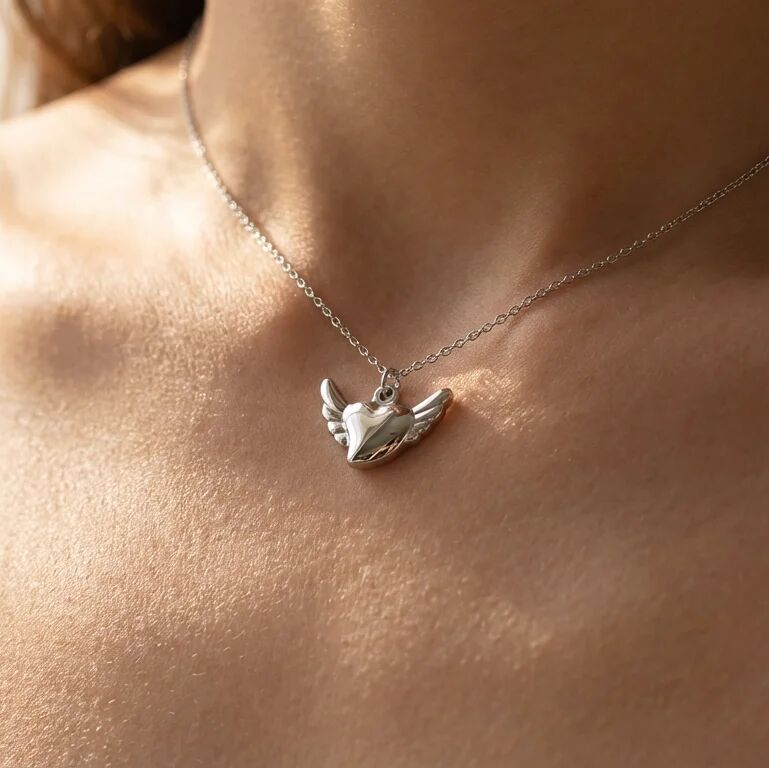 Silver necklace with a heart-shaped pendant on a person's neck