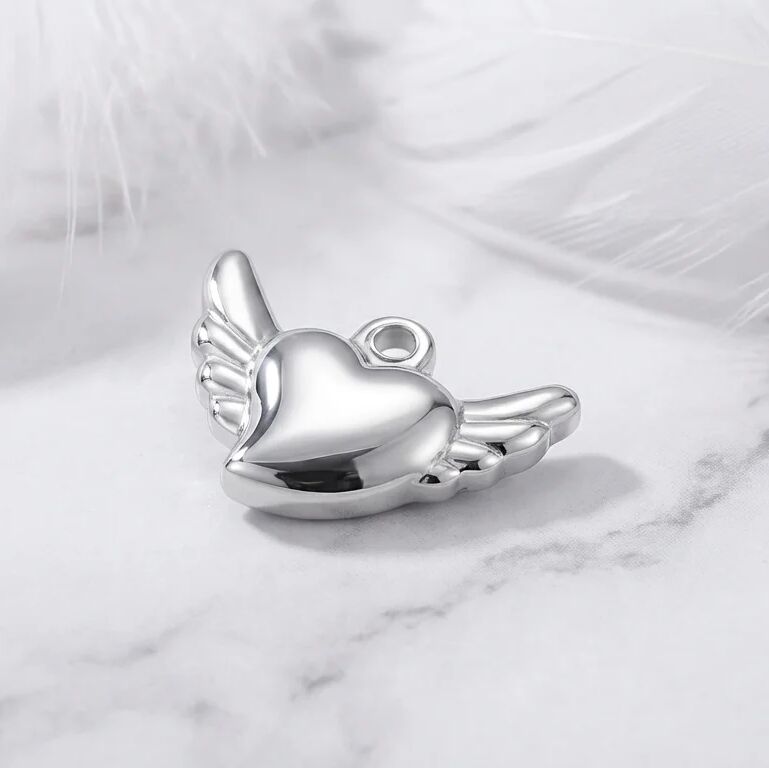 Silver heart-shaped pendant with wings on a marble surface