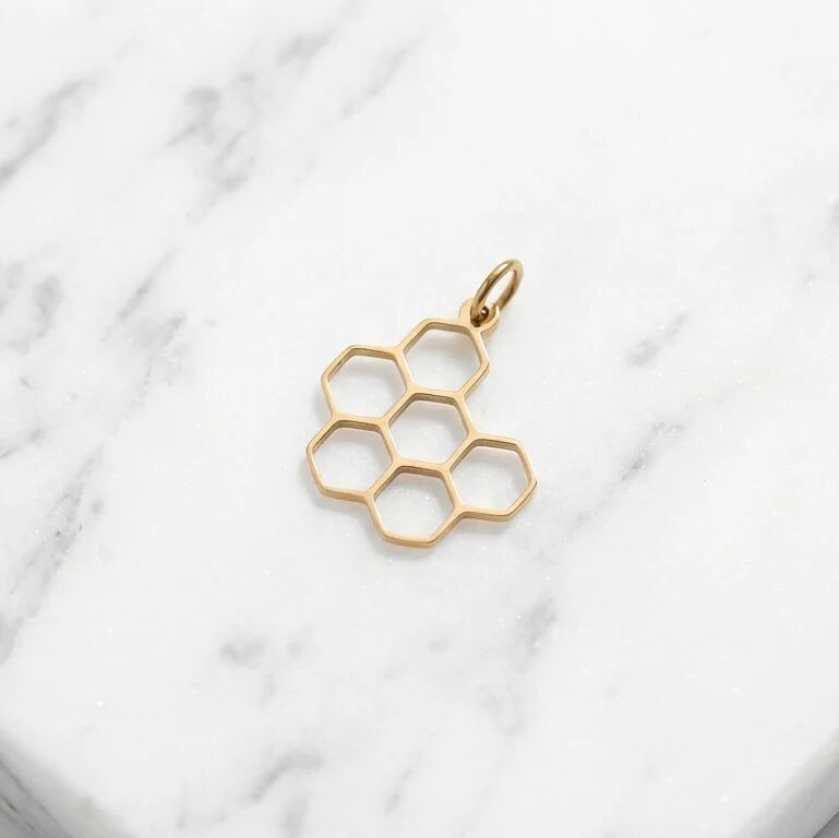 Gold honeycomb pendant on a marble surface