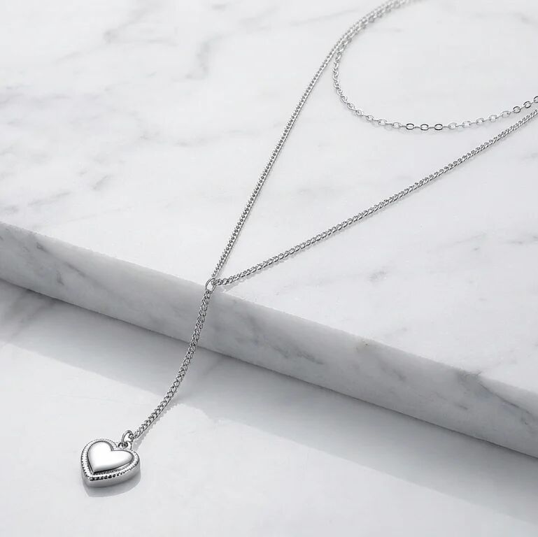 Silver heart-shaped pendant necklace on a marble surface