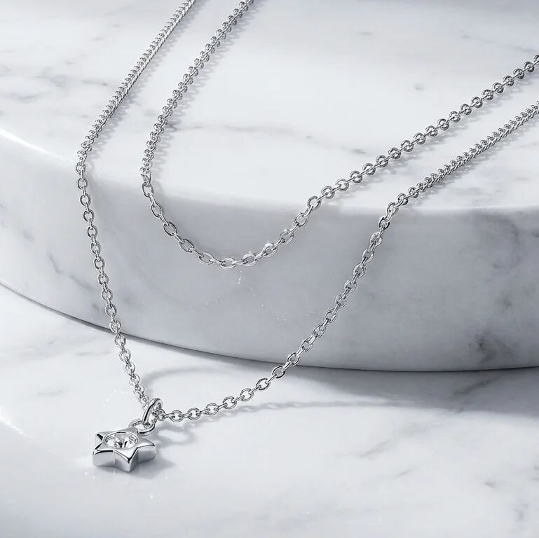 Layered silver necklaces on a marble surface