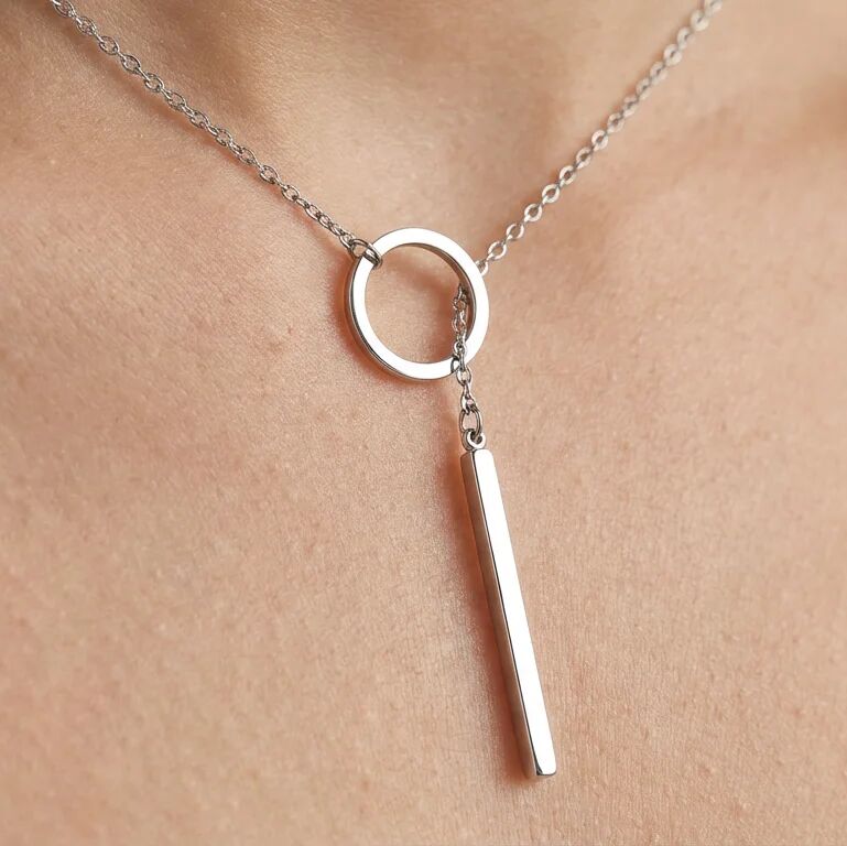 Silver necklace with a circular pendant and a vertical bar on a neck