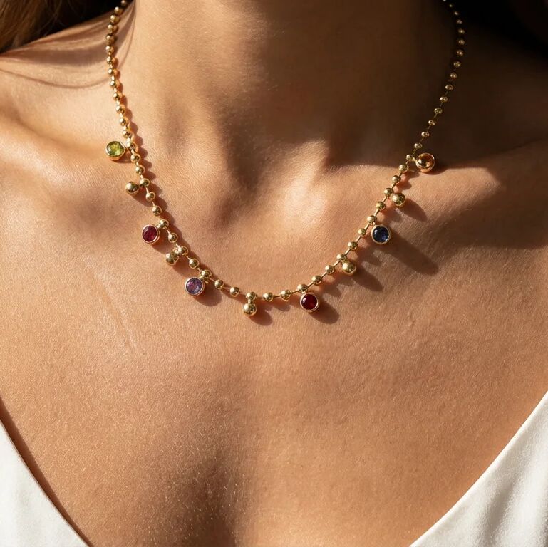 Necklace with multicolored beads on a person wearing a white top.