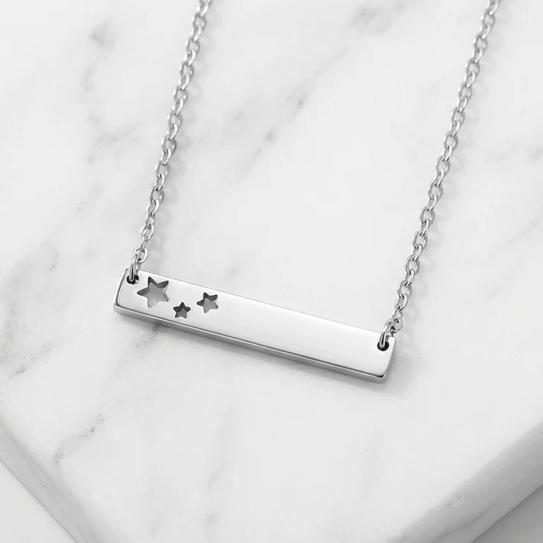 Silver necklace with star designs on a marble surface