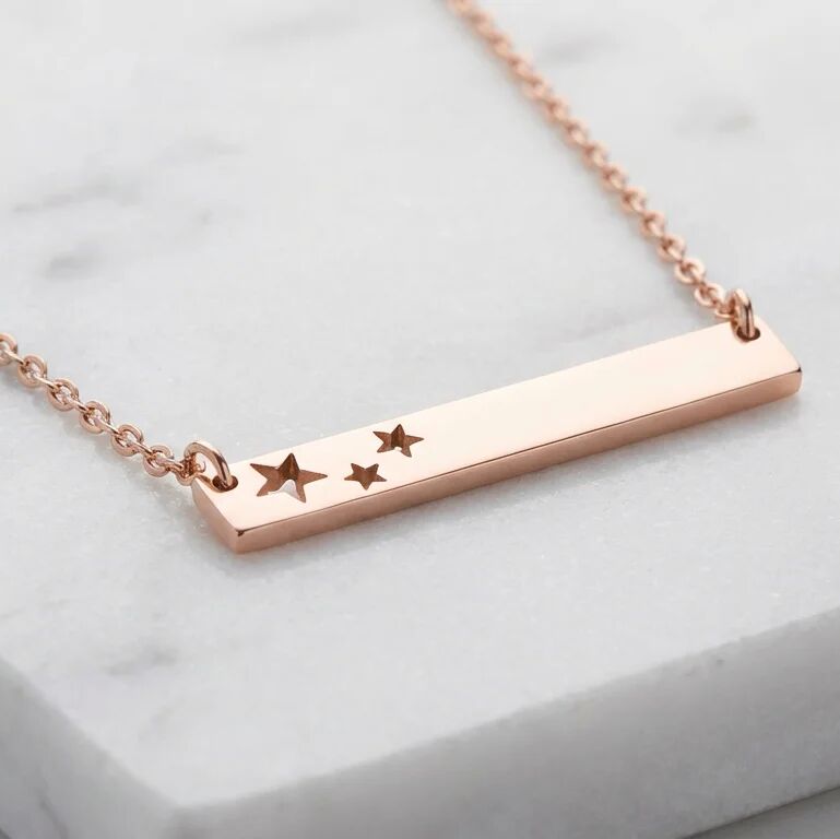 Rose gold necklace with star charms on a light gray background