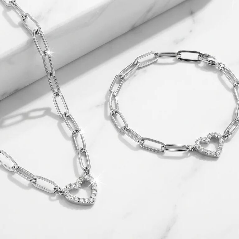 Silver chain necklace and bracelet with heart-shaped links on a light background
