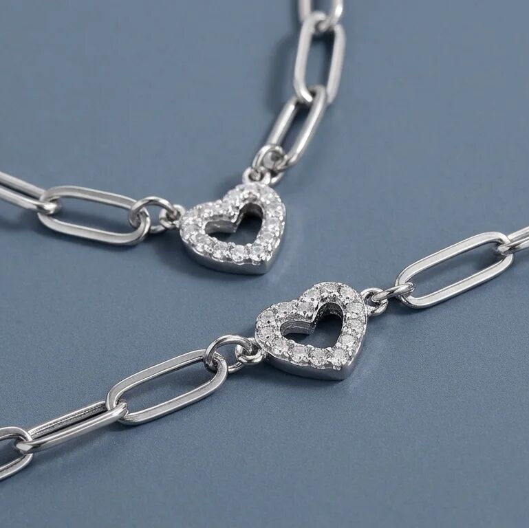 Silver chain necklace with heart-shaped pendants on a blue background