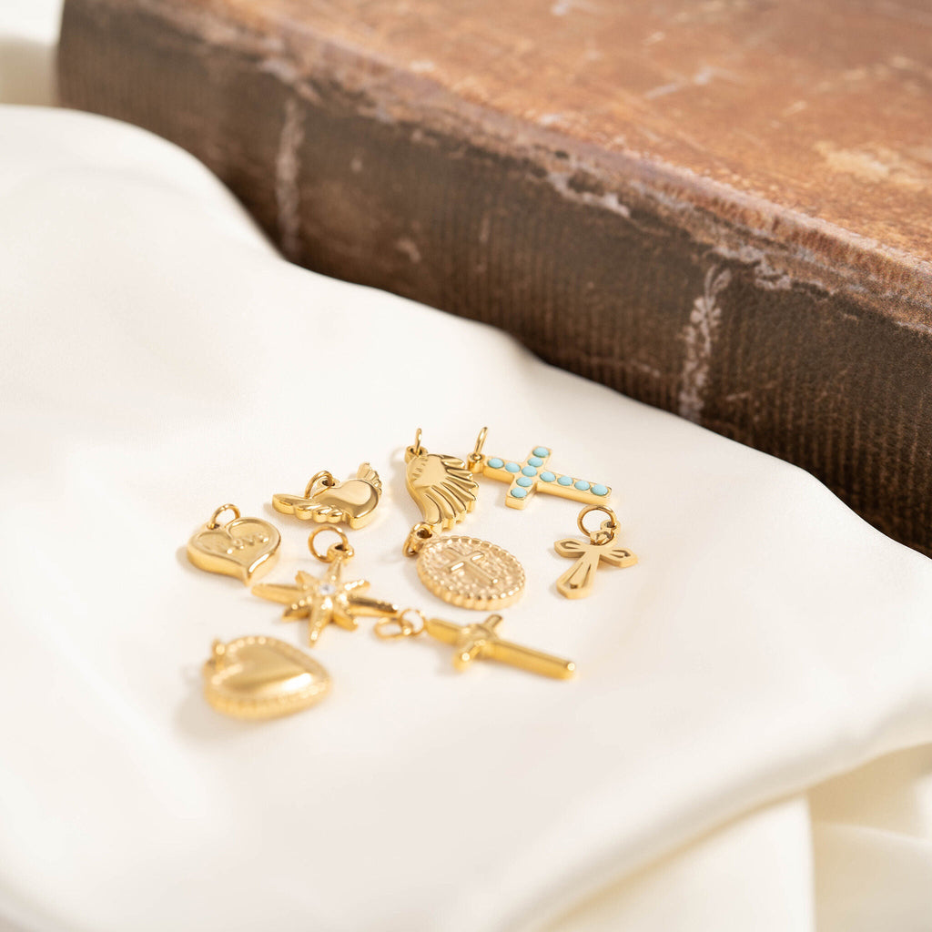 Gold charm bracelet on a white surface with a wooden block in the background