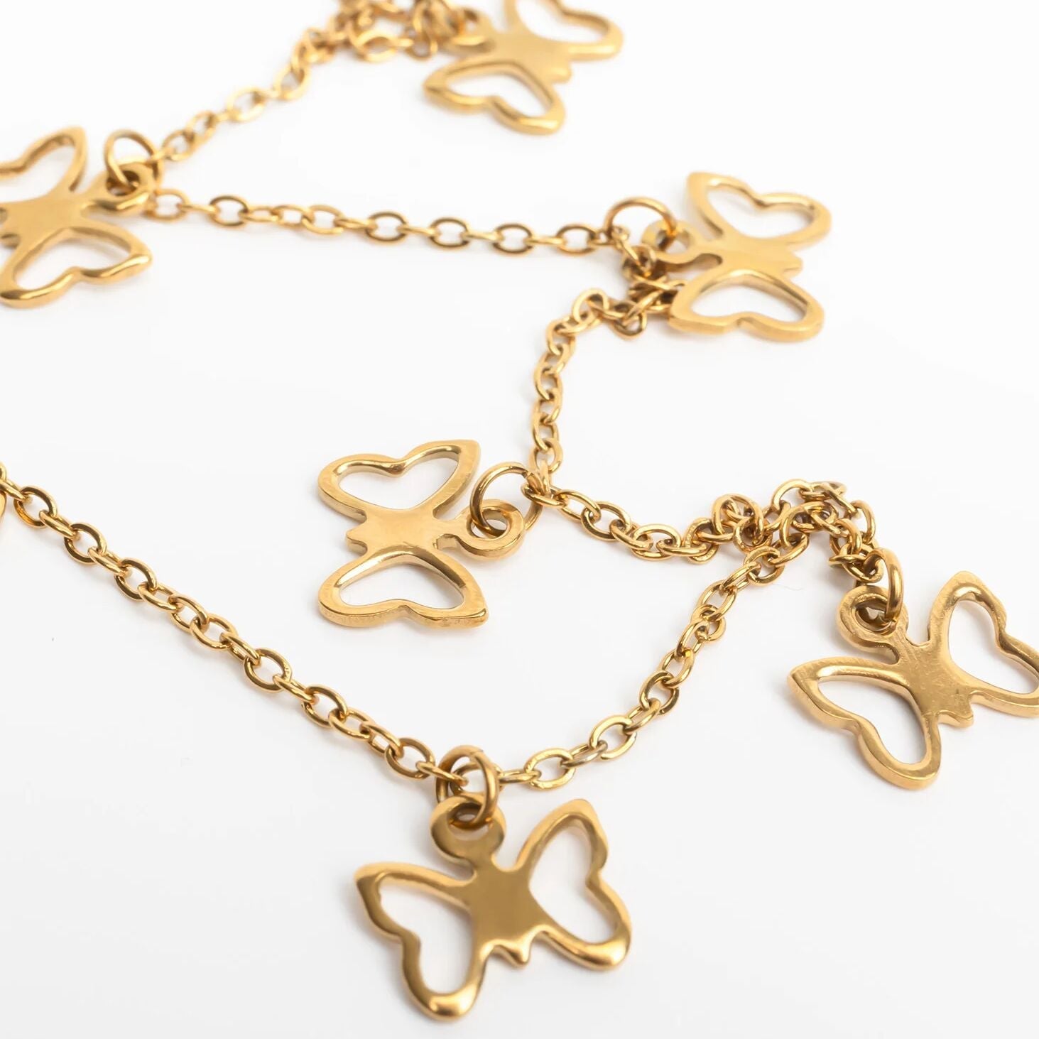 Gold butterfly necklace on a white background