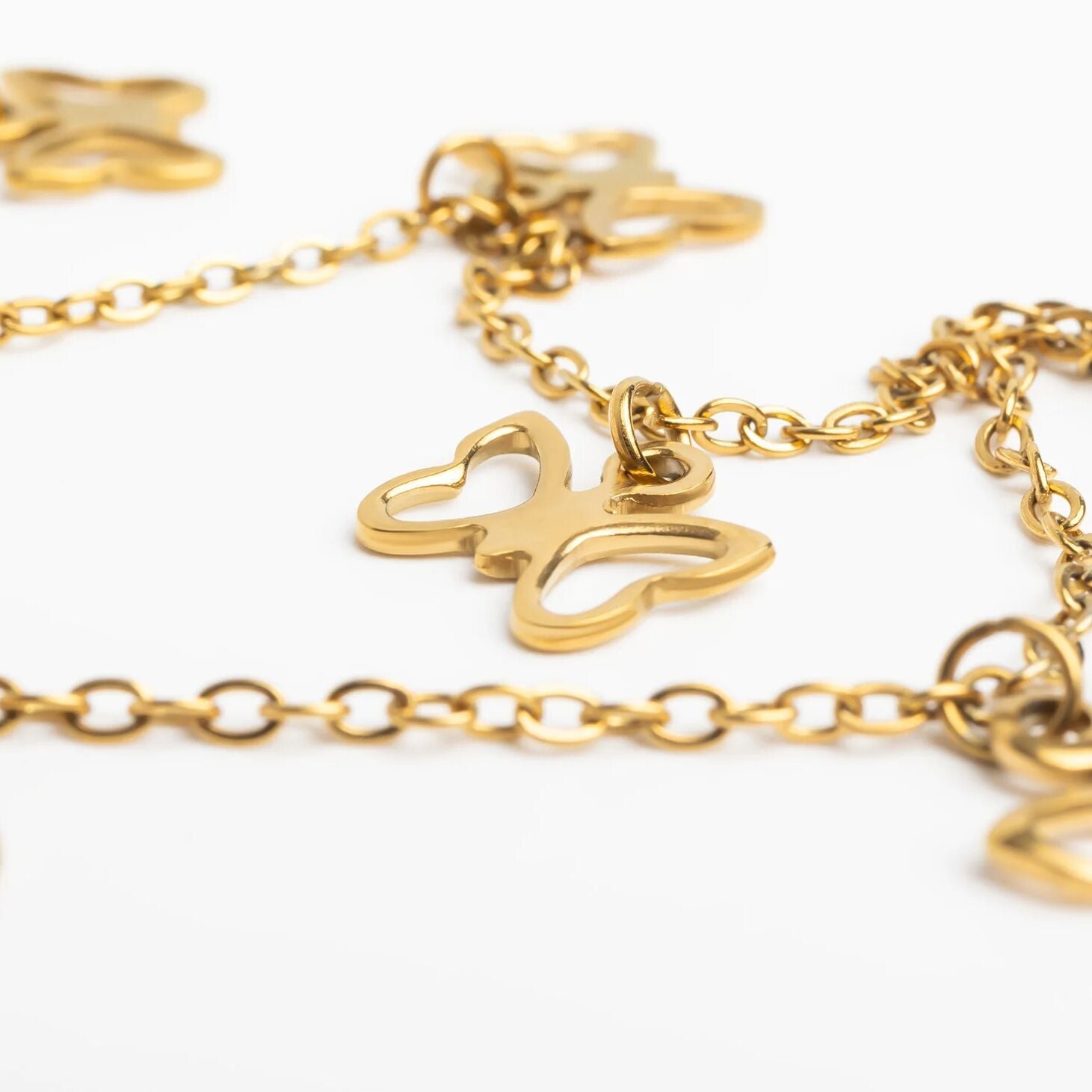 Gold bracelet with butterfly charm on a white background