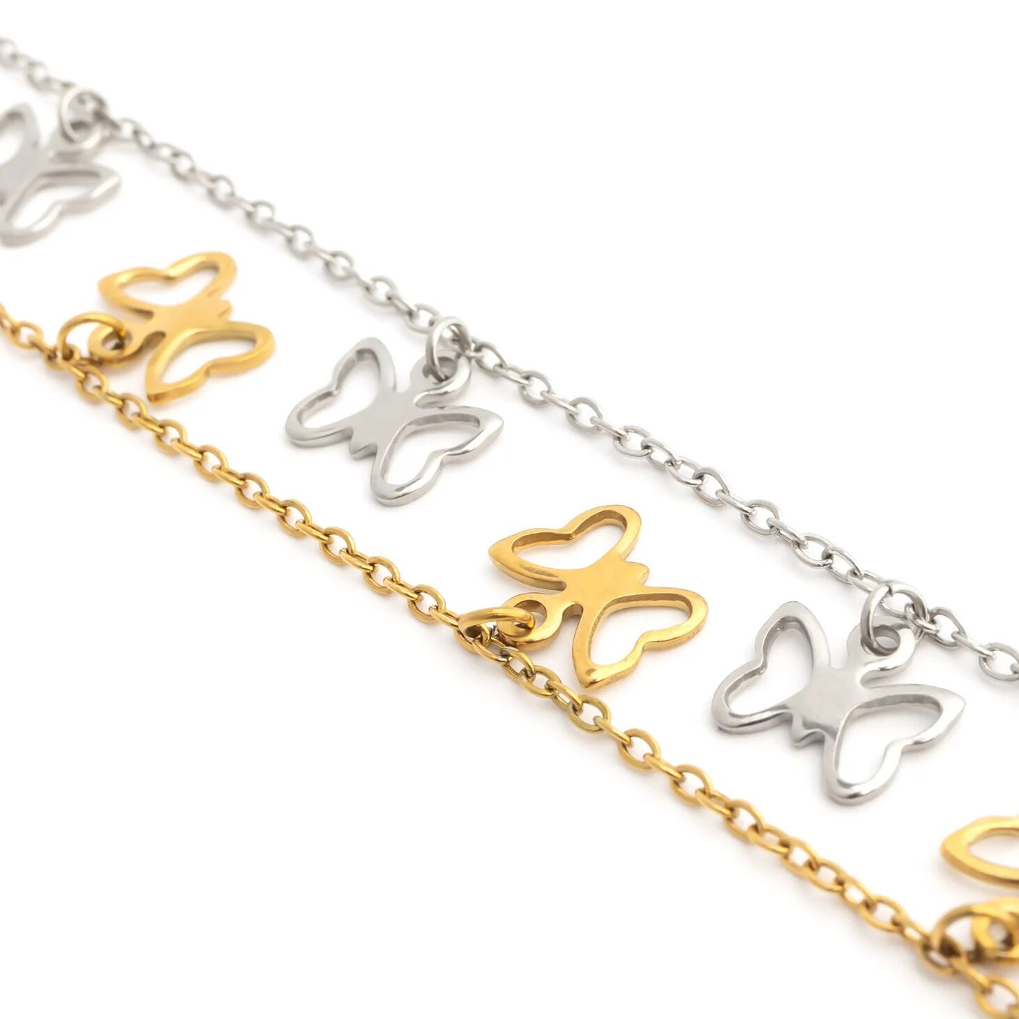 Butterfly-shaped charms on gold and silver chains against a white background