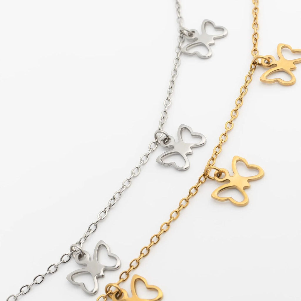Butterfly-shaped necklace in silver and gold on a white background