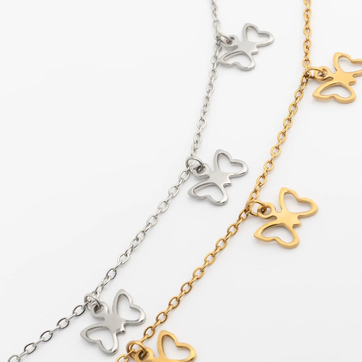 Butterfly-shaped necklace in silver and gold on a white background