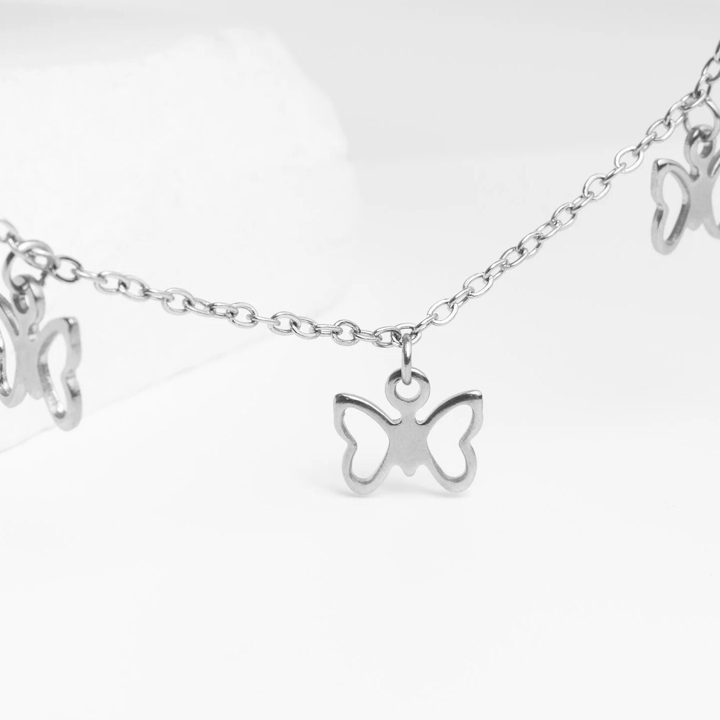 Silver butterfly charm necklace on a white background
