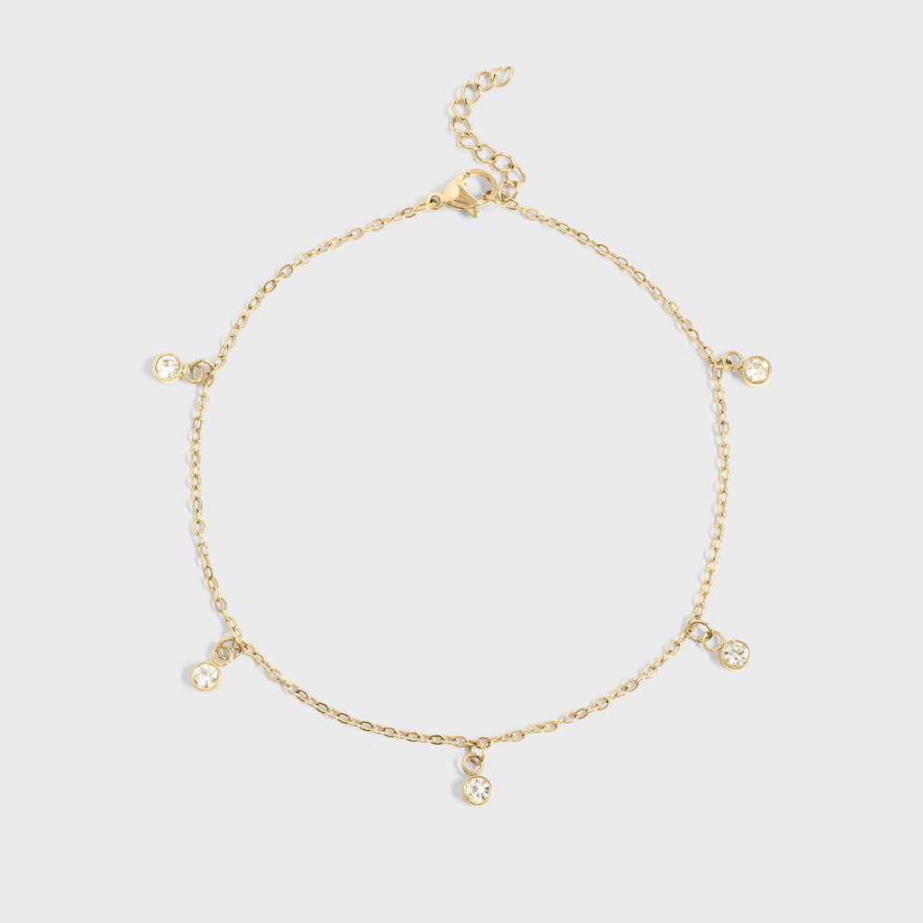 Gold bracelet with small charms on a light gray background