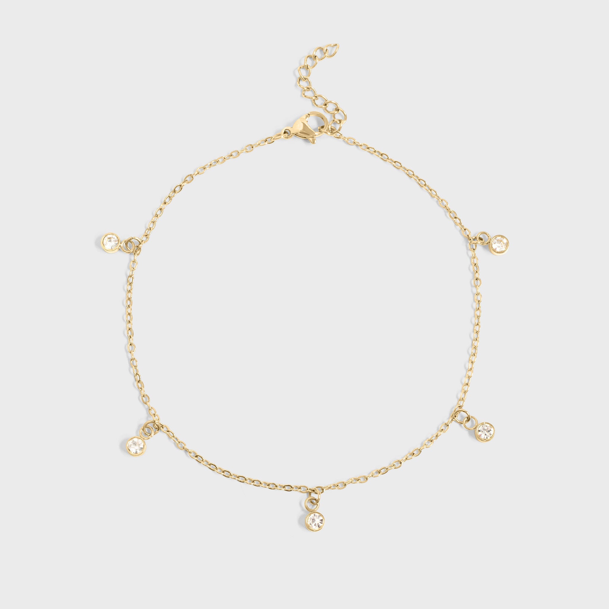 Gold bracelet with small charms on a light gray background