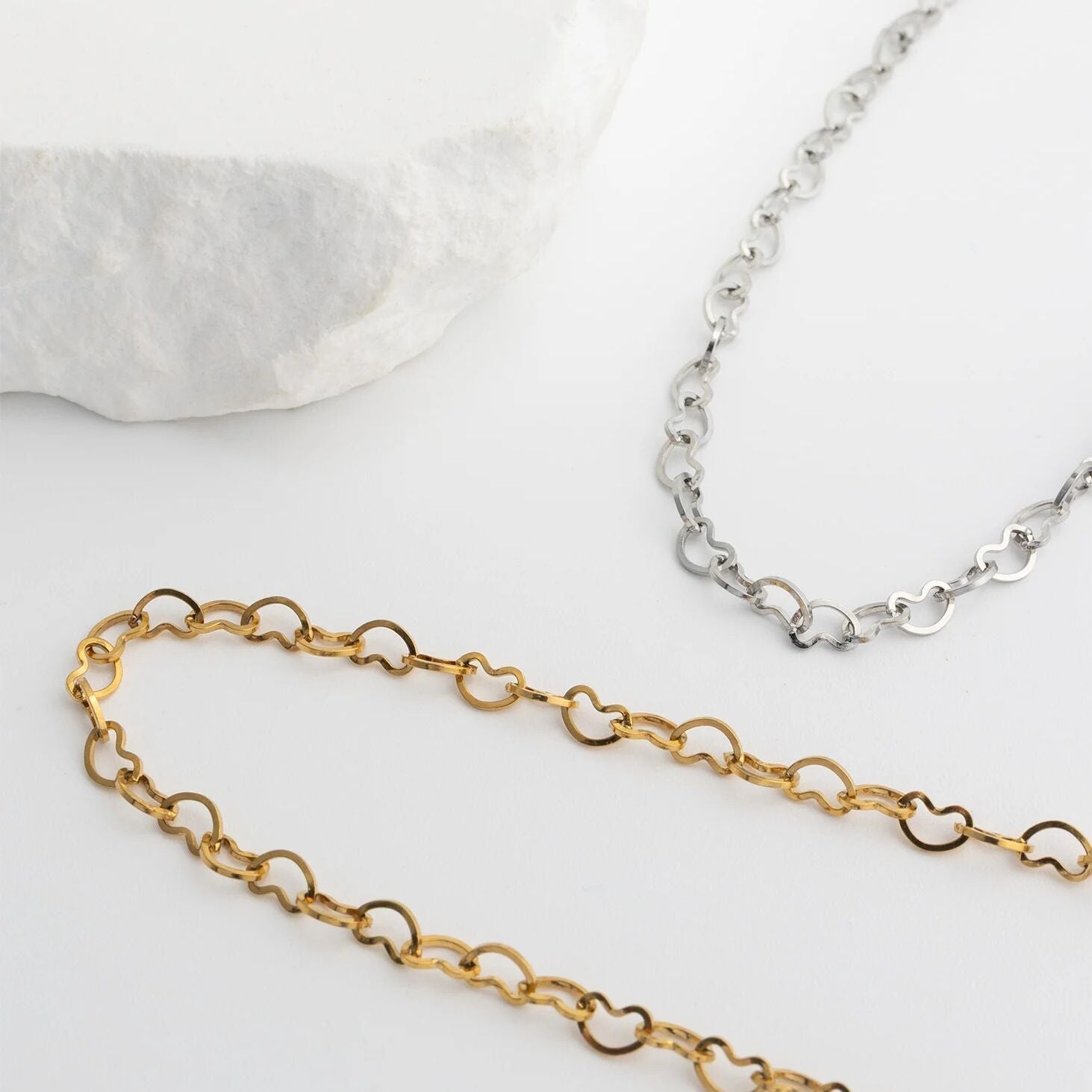 Gold and silver chain Linked Hearts Anklets on a light background