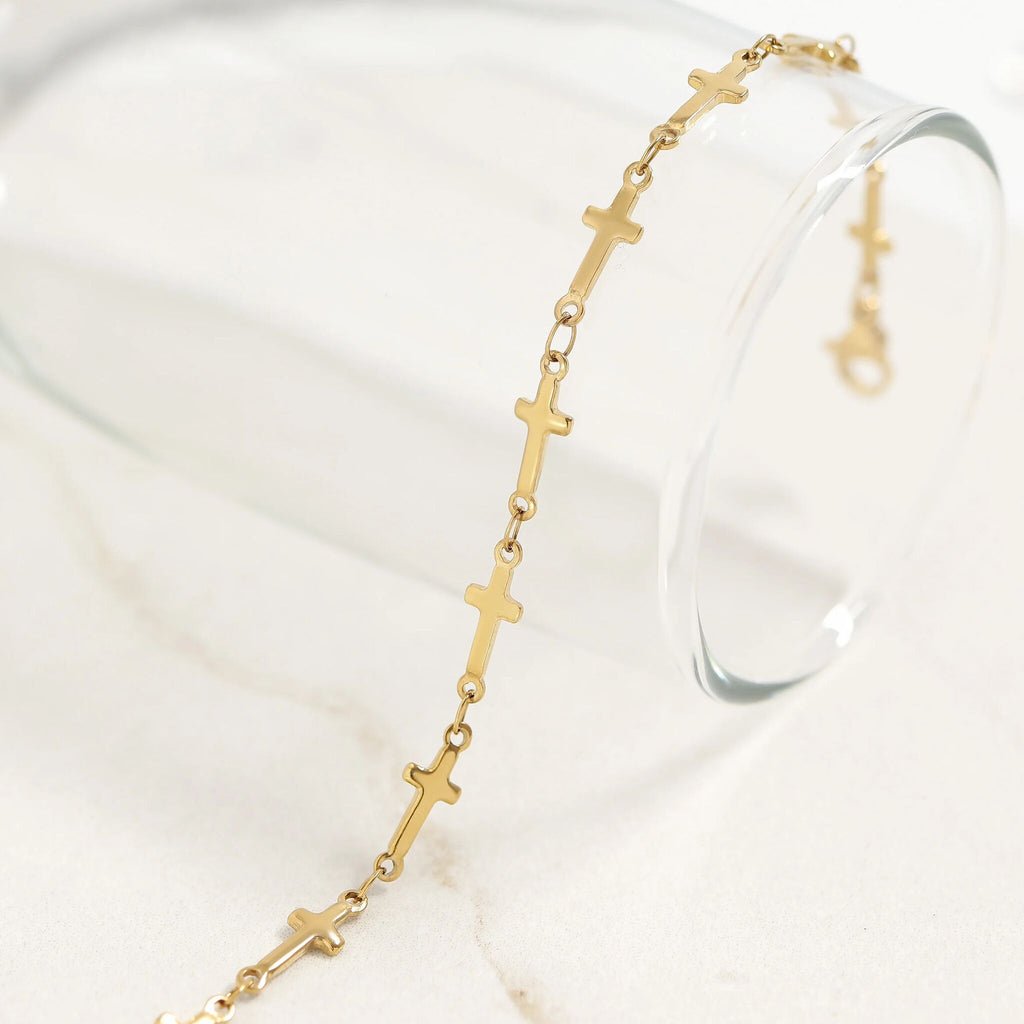 Gold bracelet with cross designs on a white surface