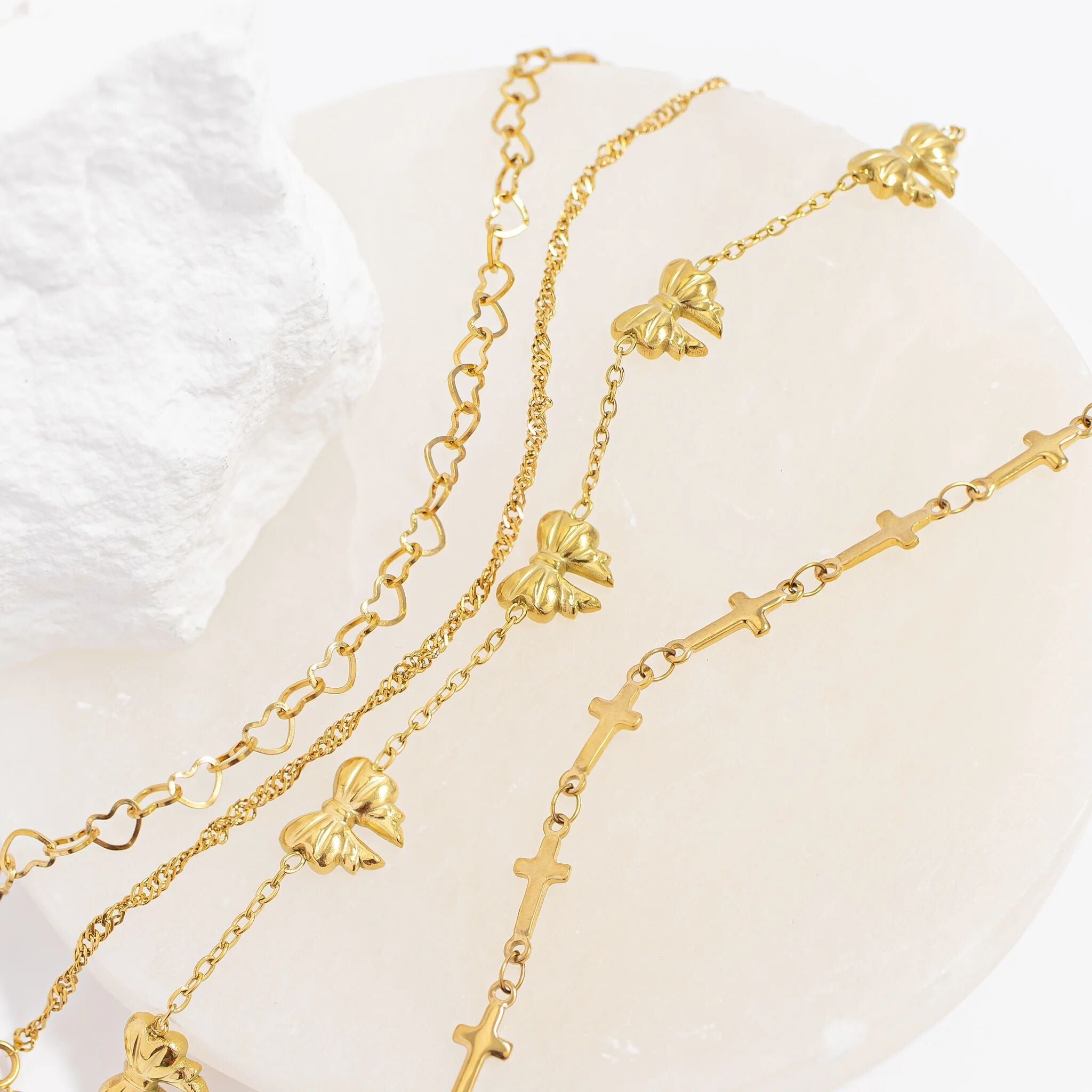 Two gold necklaces with floral and cross designs on a white background