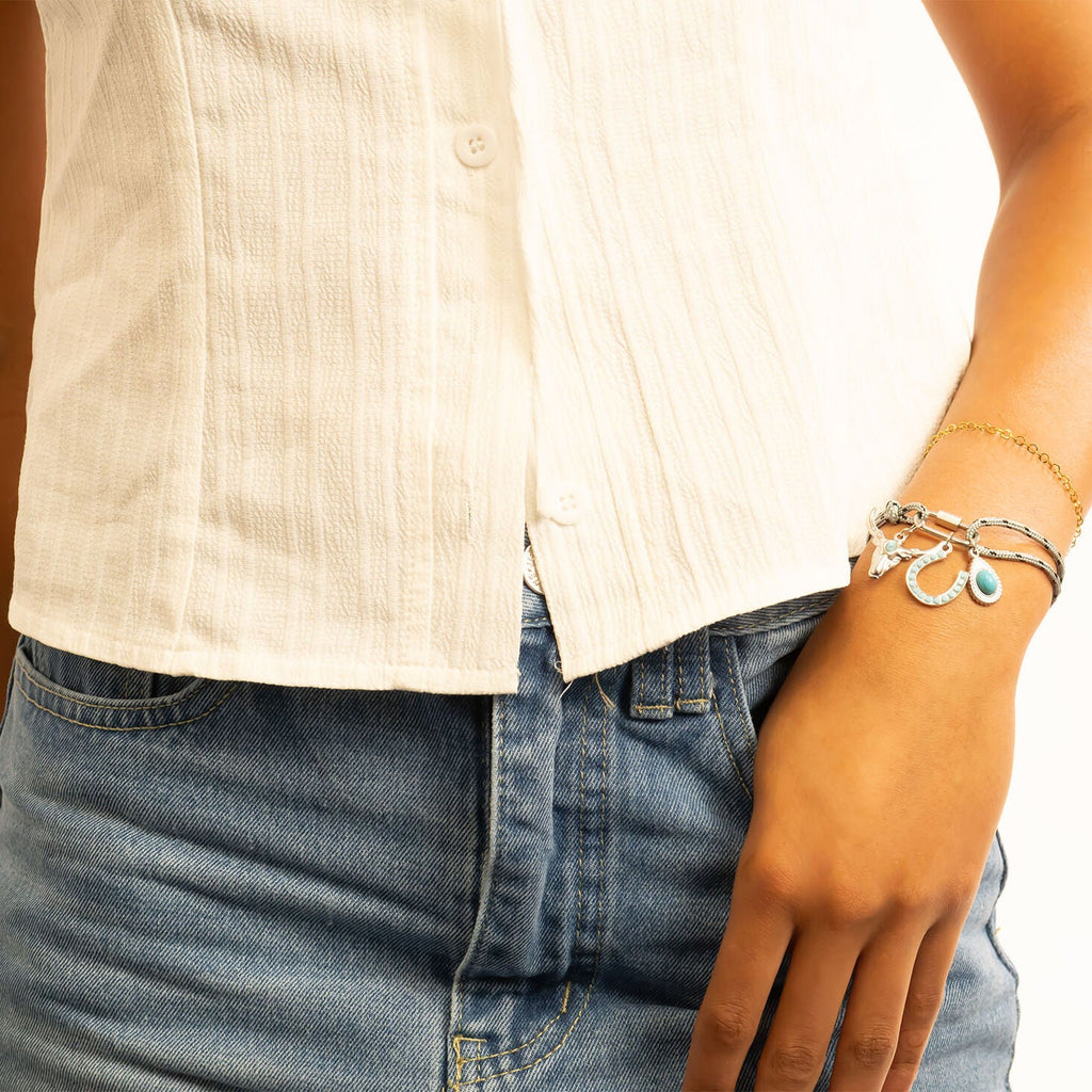 Person wearing a white shirt and blue jeans with visible jewelry including the Turquoise Tear Drop Charm in silver.