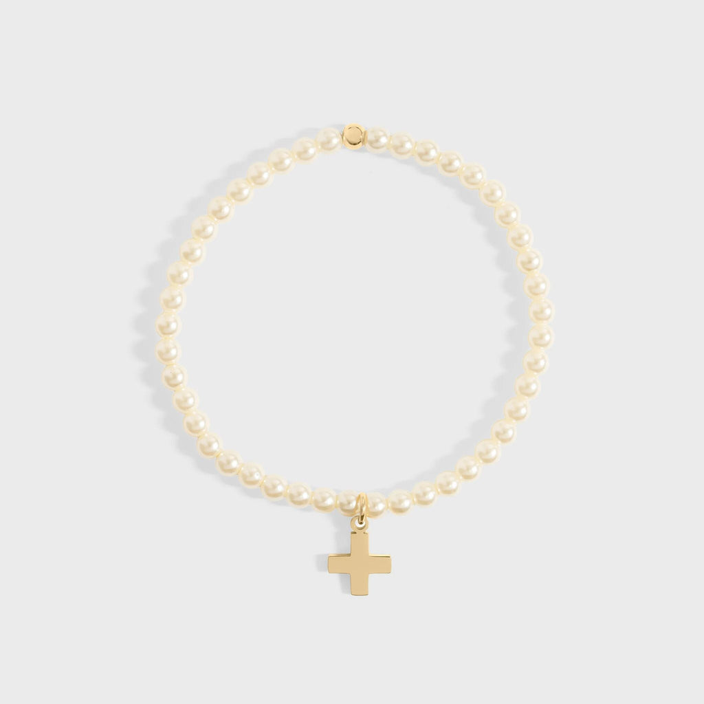 Gold bracelet with a cross charm on a light gray background