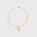 Gold bracelet with a cross charm on a light gray background