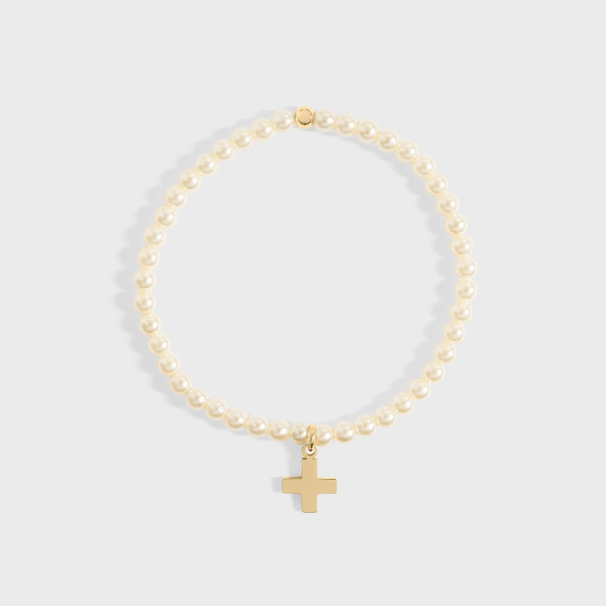 Gold bracelet with a cross charm on a light gray background
