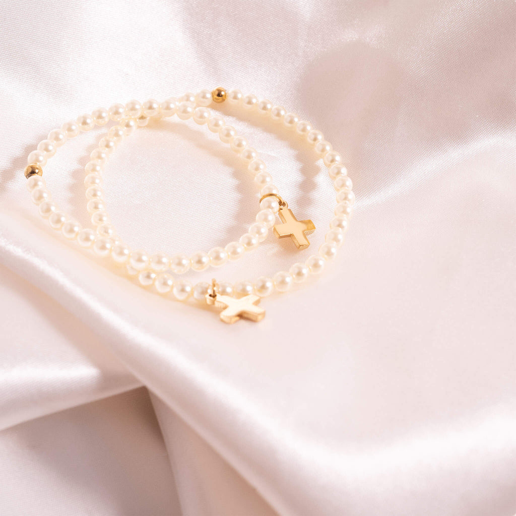 Two pearl bracelets with gold clasps on a soft pink fabric background