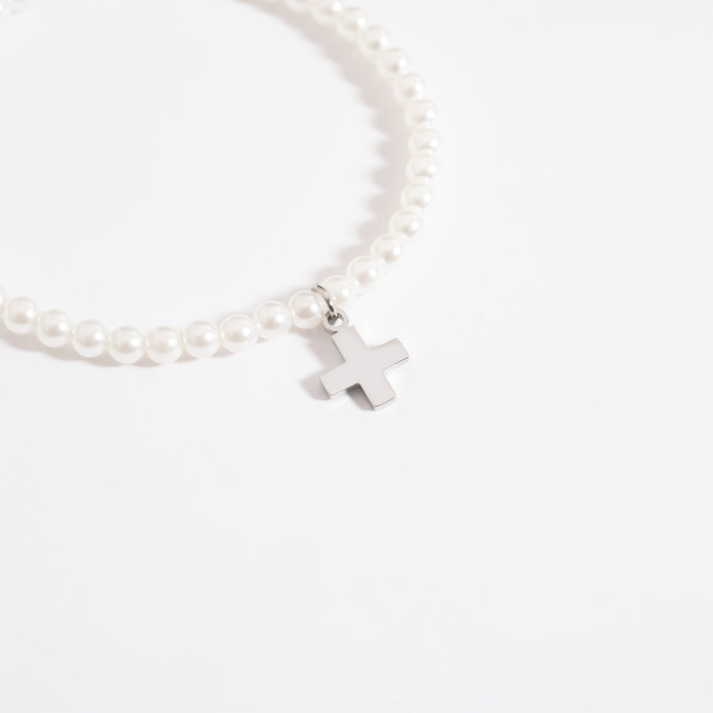 Pearl bracelet with a silver cross charm on a white background