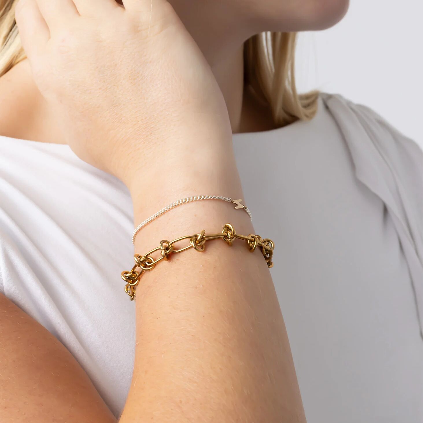 Gold bracelet on a person's wrist with a neutral background