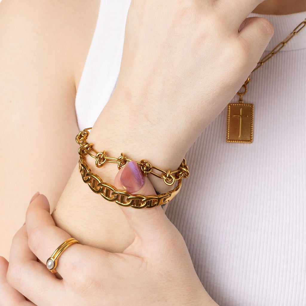 Close-up of a person's wrist wearing gold bracelets and a necklace with a cross pendant.