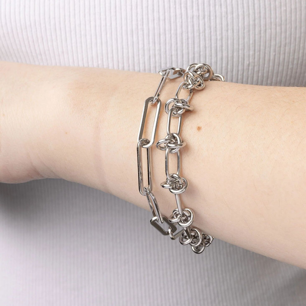 Silver chain bracelet on a wrist against a light background