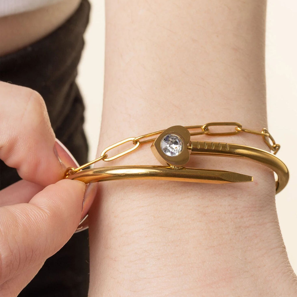 Gold bracelet with a heart-shaped clasp worn on a wrist