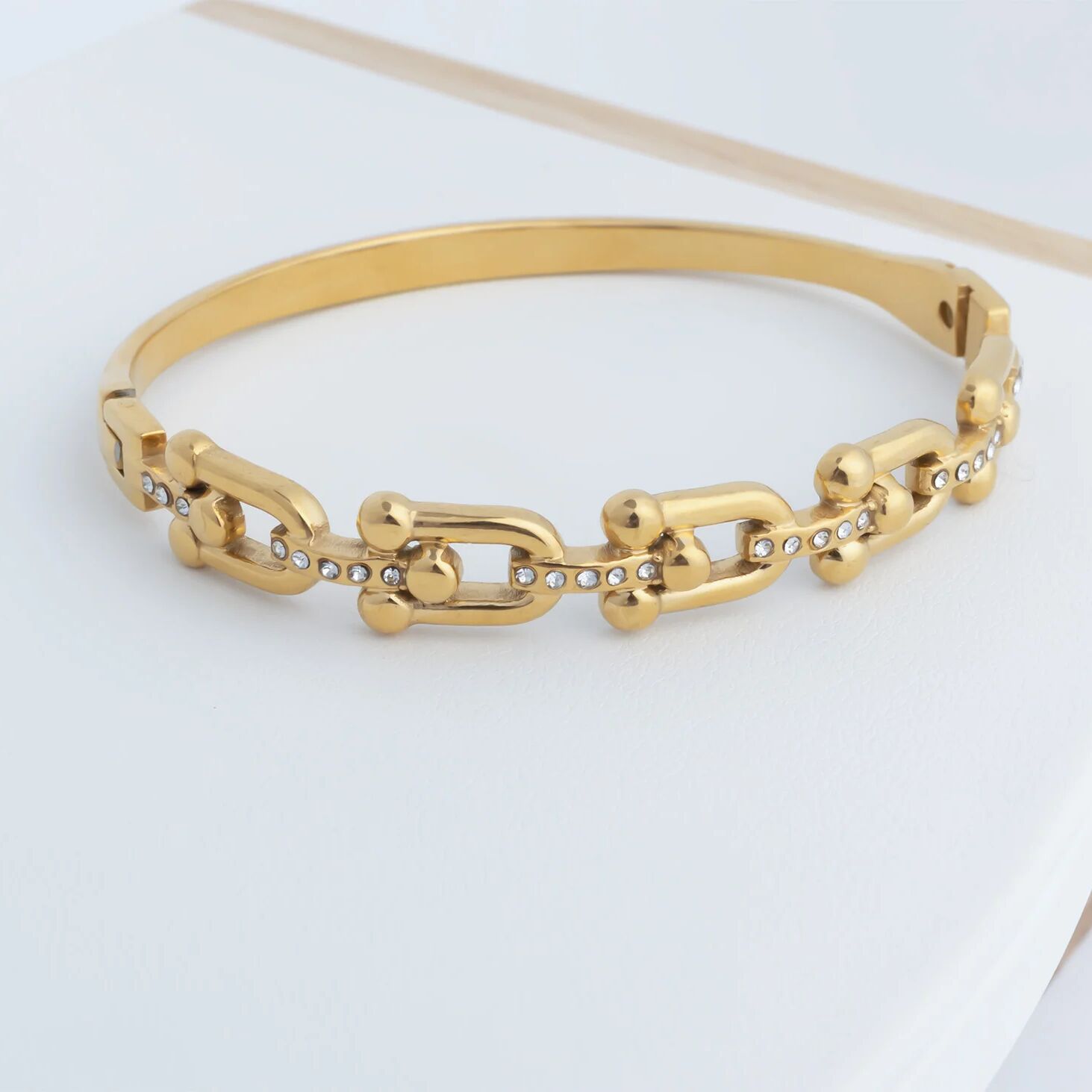 Gold chain bracelet on a light gray background