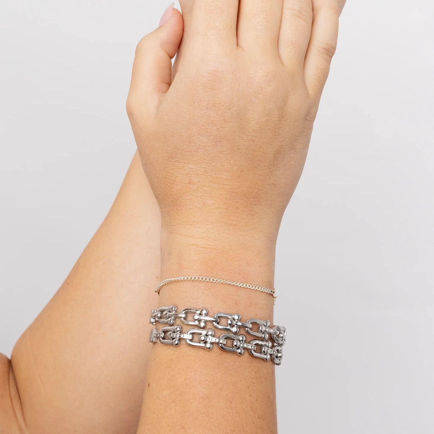 Silver chain bracelet on a wrist against a plain background