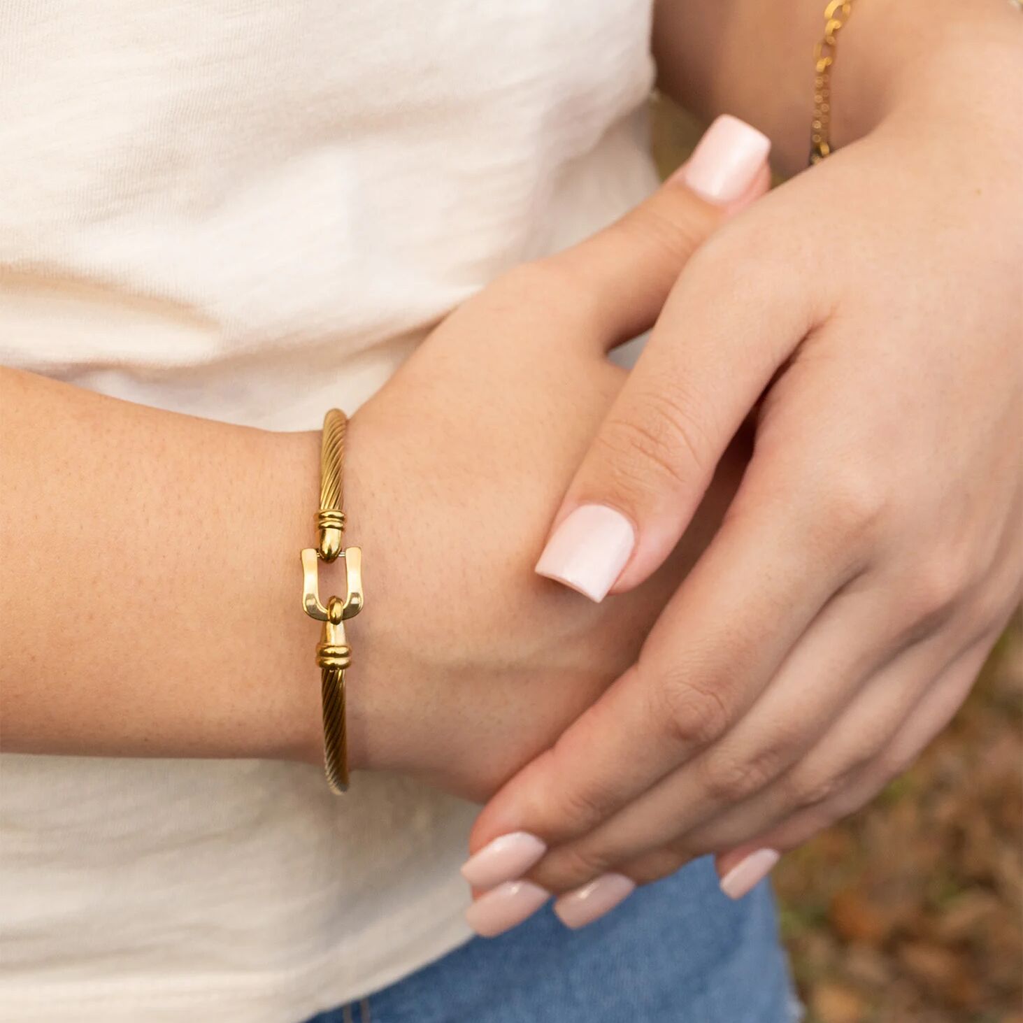 Close-up of a person wearing a gold bracelet with a blurred background