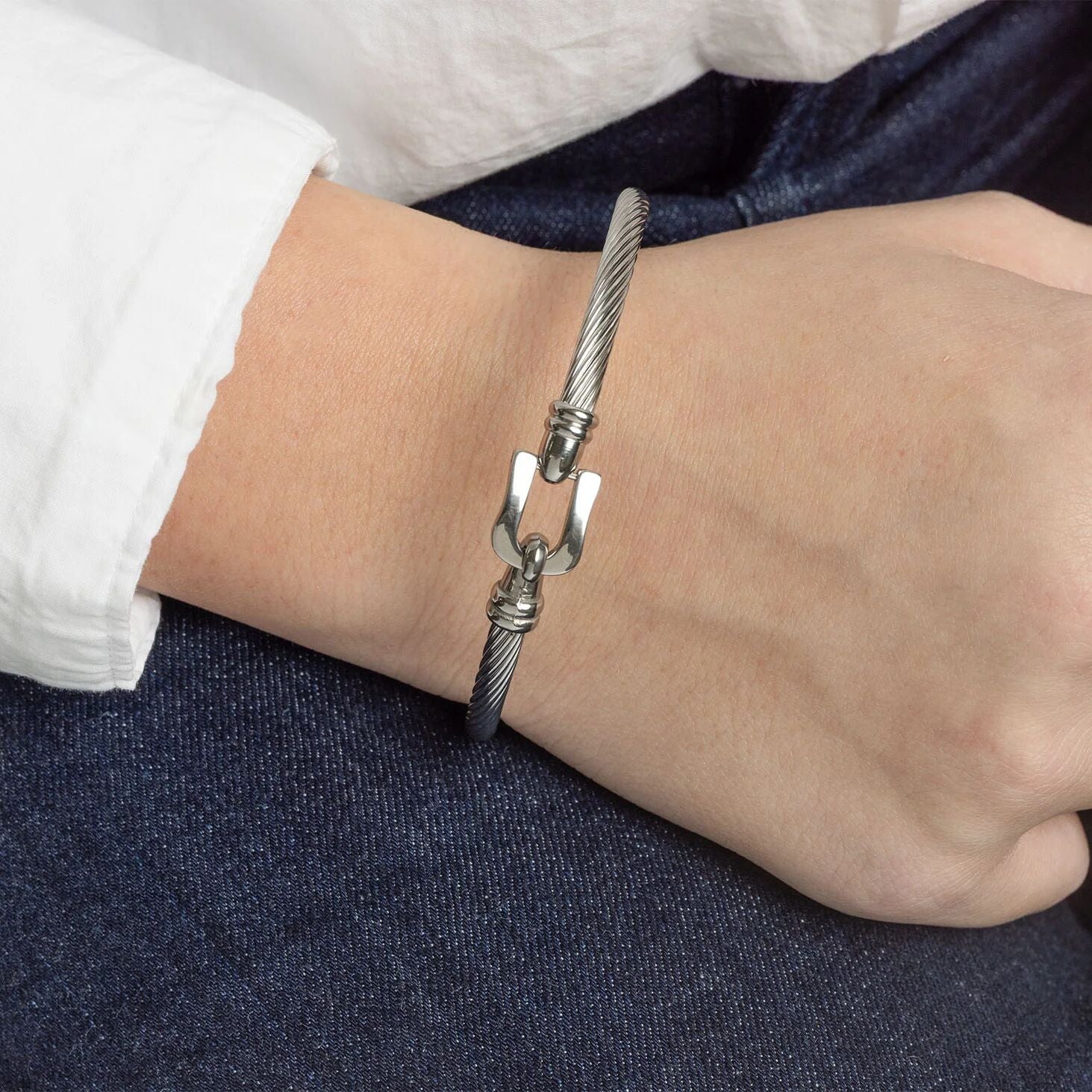 Silver bracelet with a unique clasp on a wrist against a dark fabric background