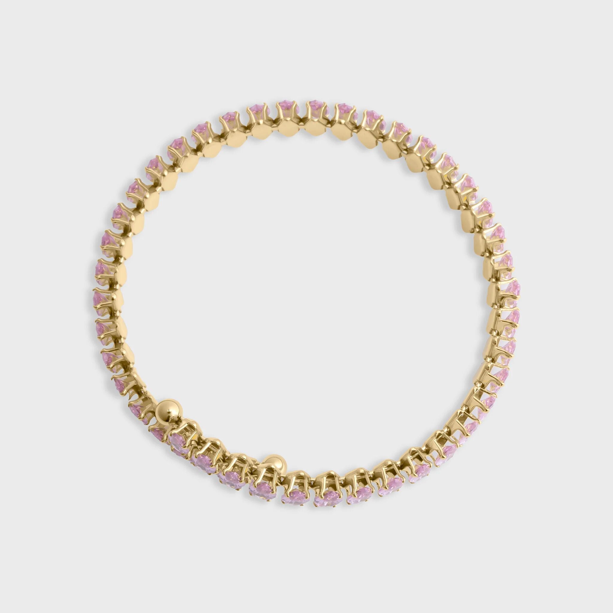 Gold bracelet with pink stones on a light gray background