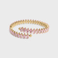 Gold bracelet with pink gemstones on a light gray background