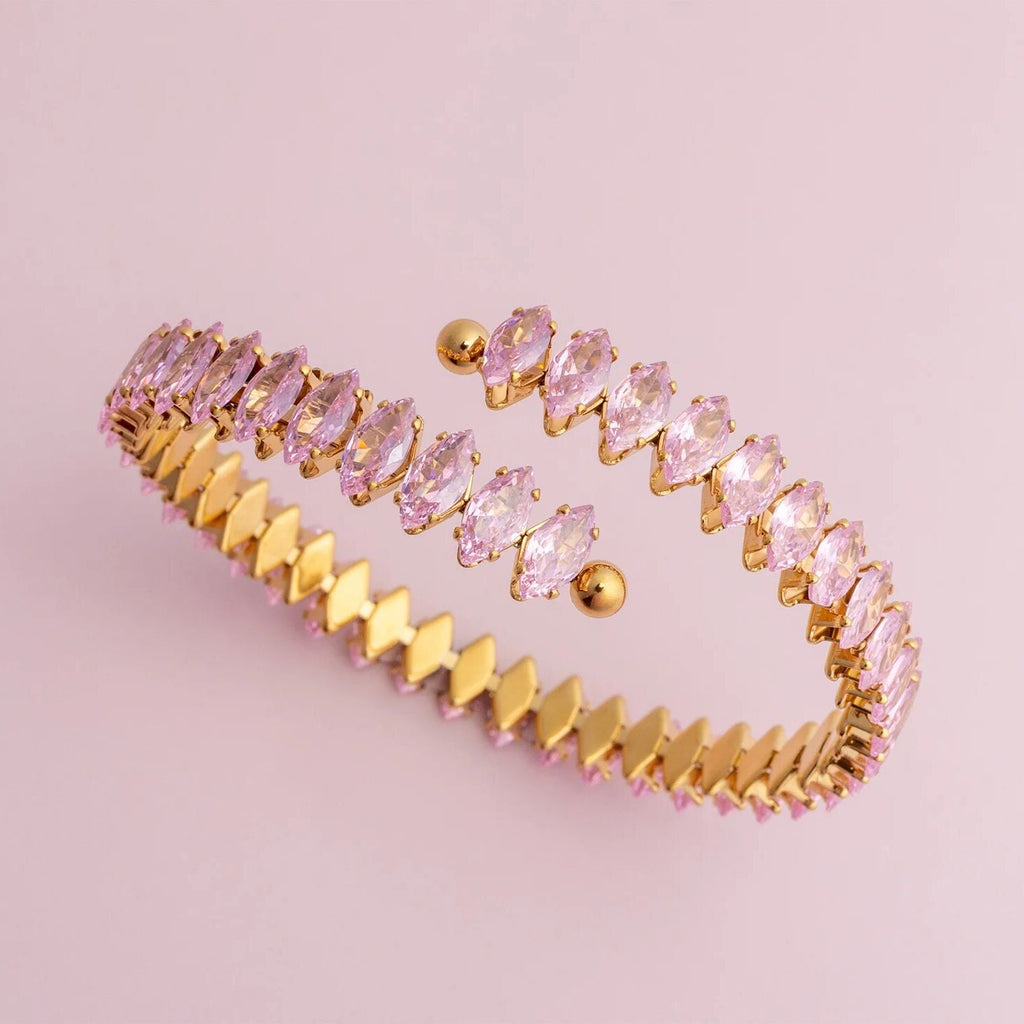 Gold bracelet with pink gemstones on a pink background