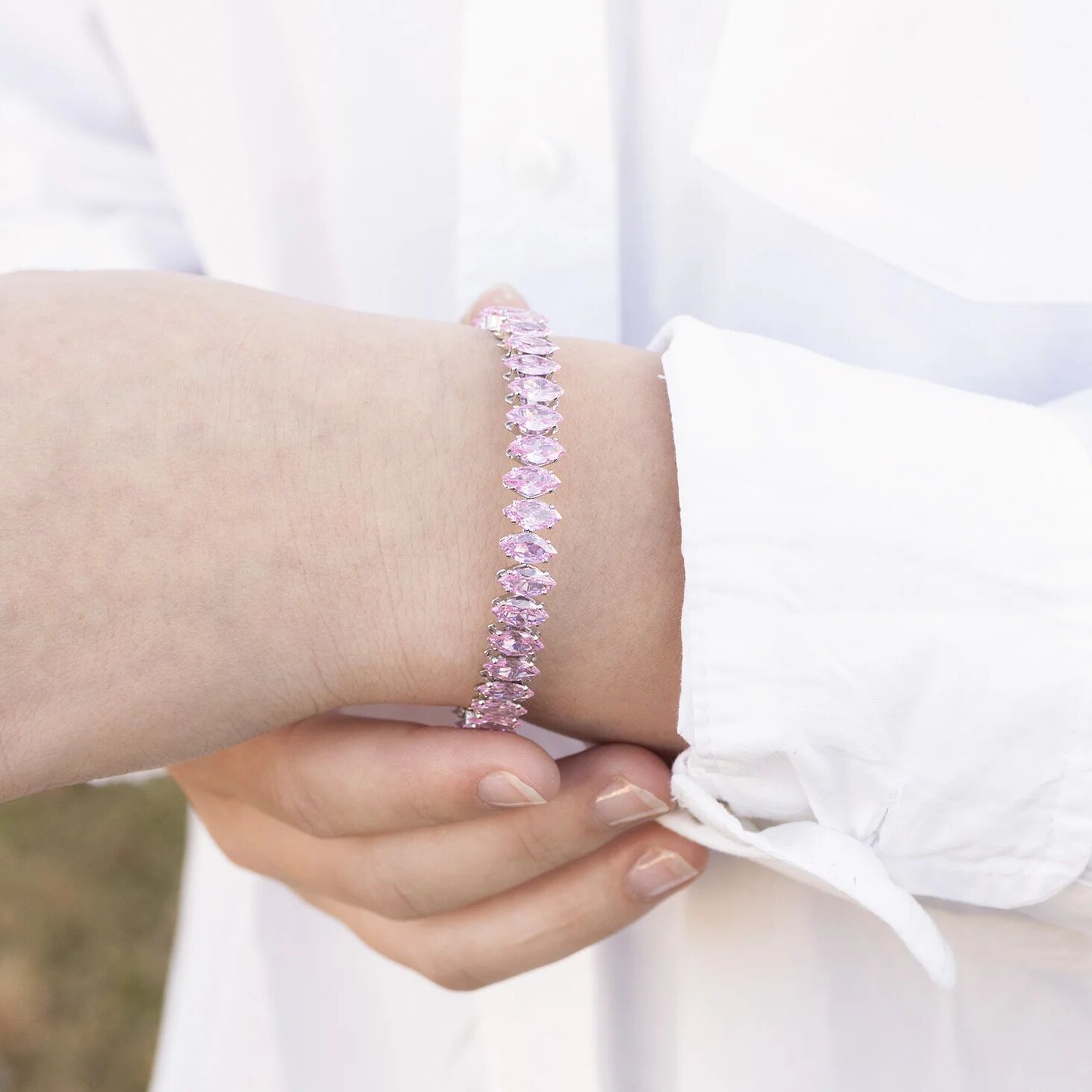 Close-up of a wrist wearing a pink beaded bracelet with a blurred background