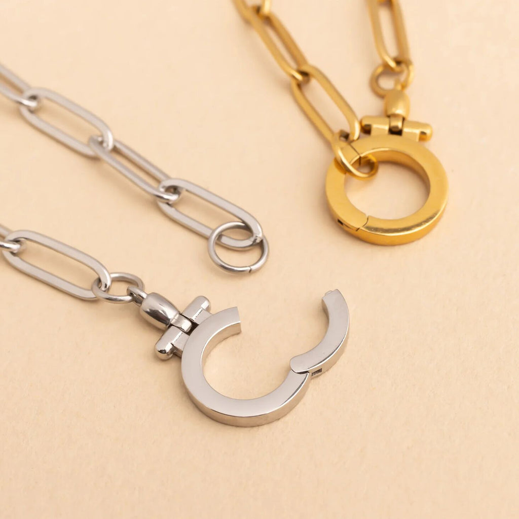 Two necklaces, one gold and one silver, on a beige background