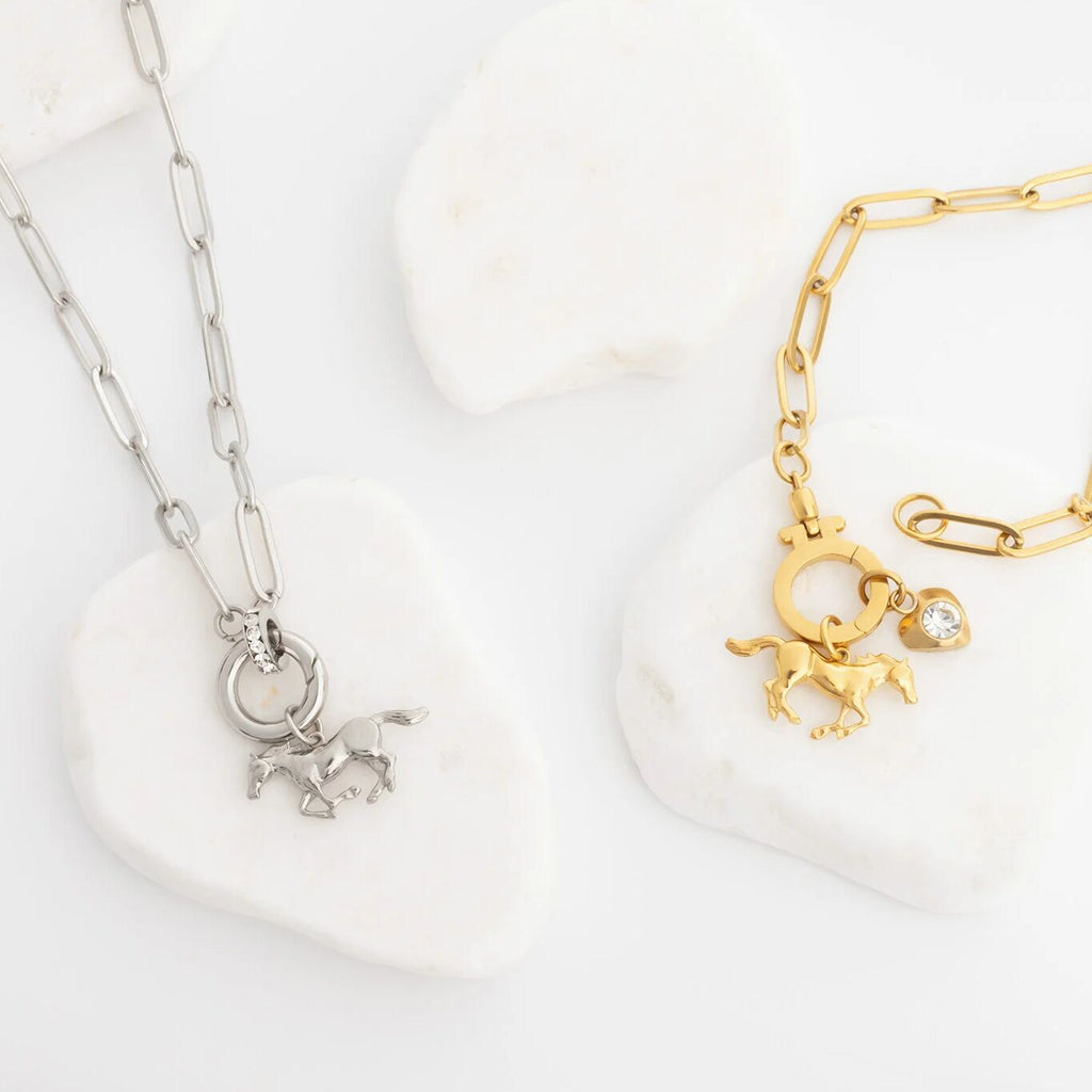 Gold and silver necklaces with horse charms on a white background