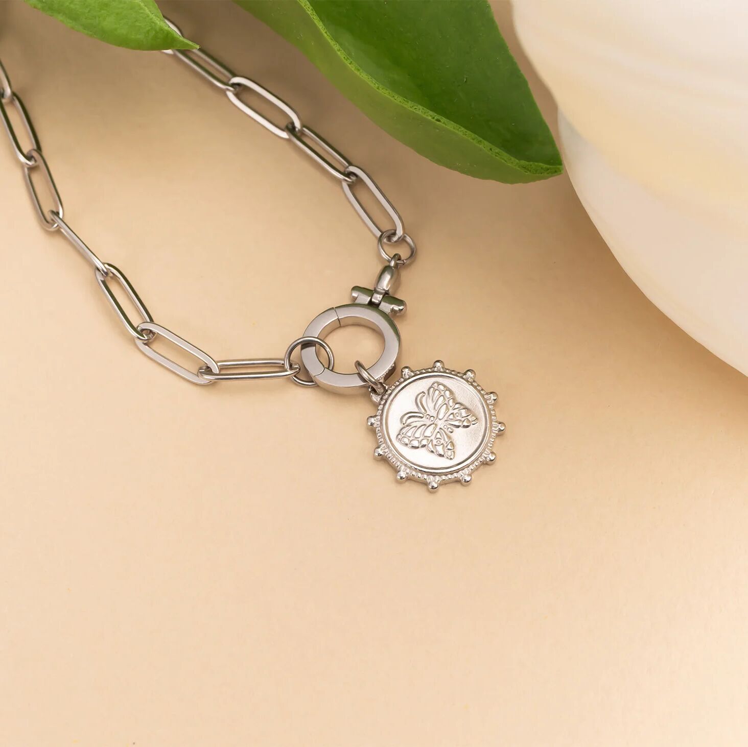 Silver bracelet with a butterfly charm on a beige background
