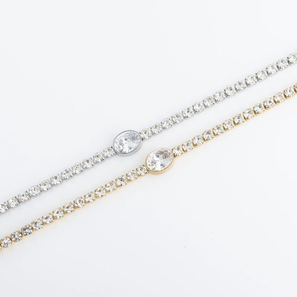 Two gold and silver bracelets with clear stones on a white background