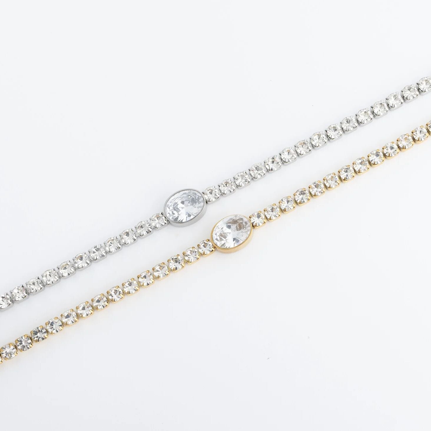 Two gold and silver bracelets with clear stones on a white background
