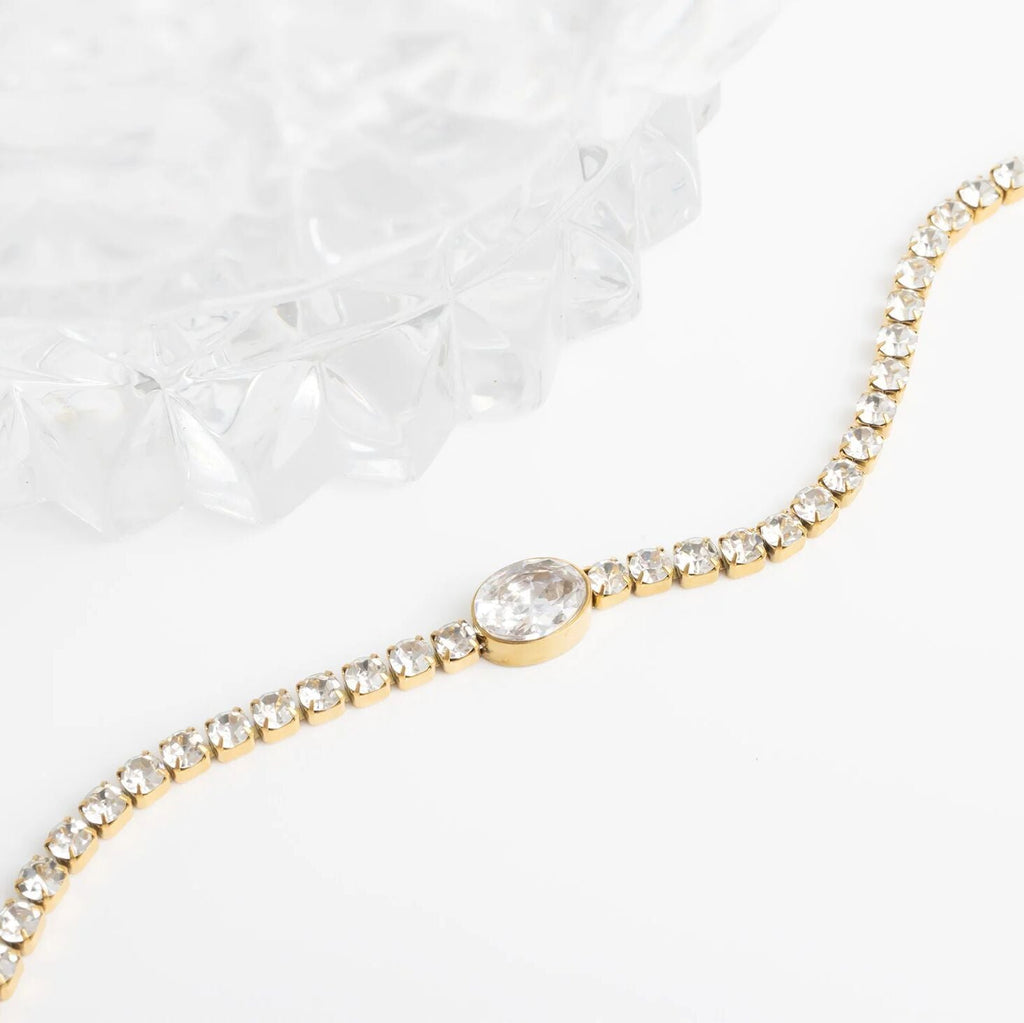 Gold bracelet with a central gemstone on a white background