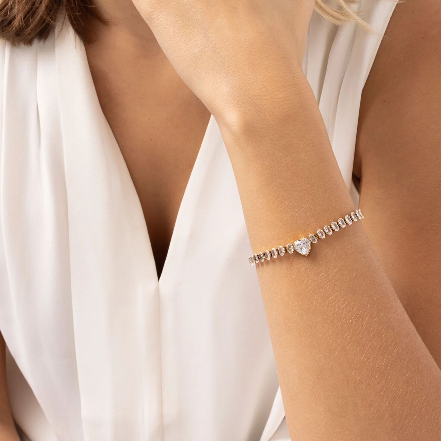 Close-up of a person wearing a delicate bracelet on a plain background
