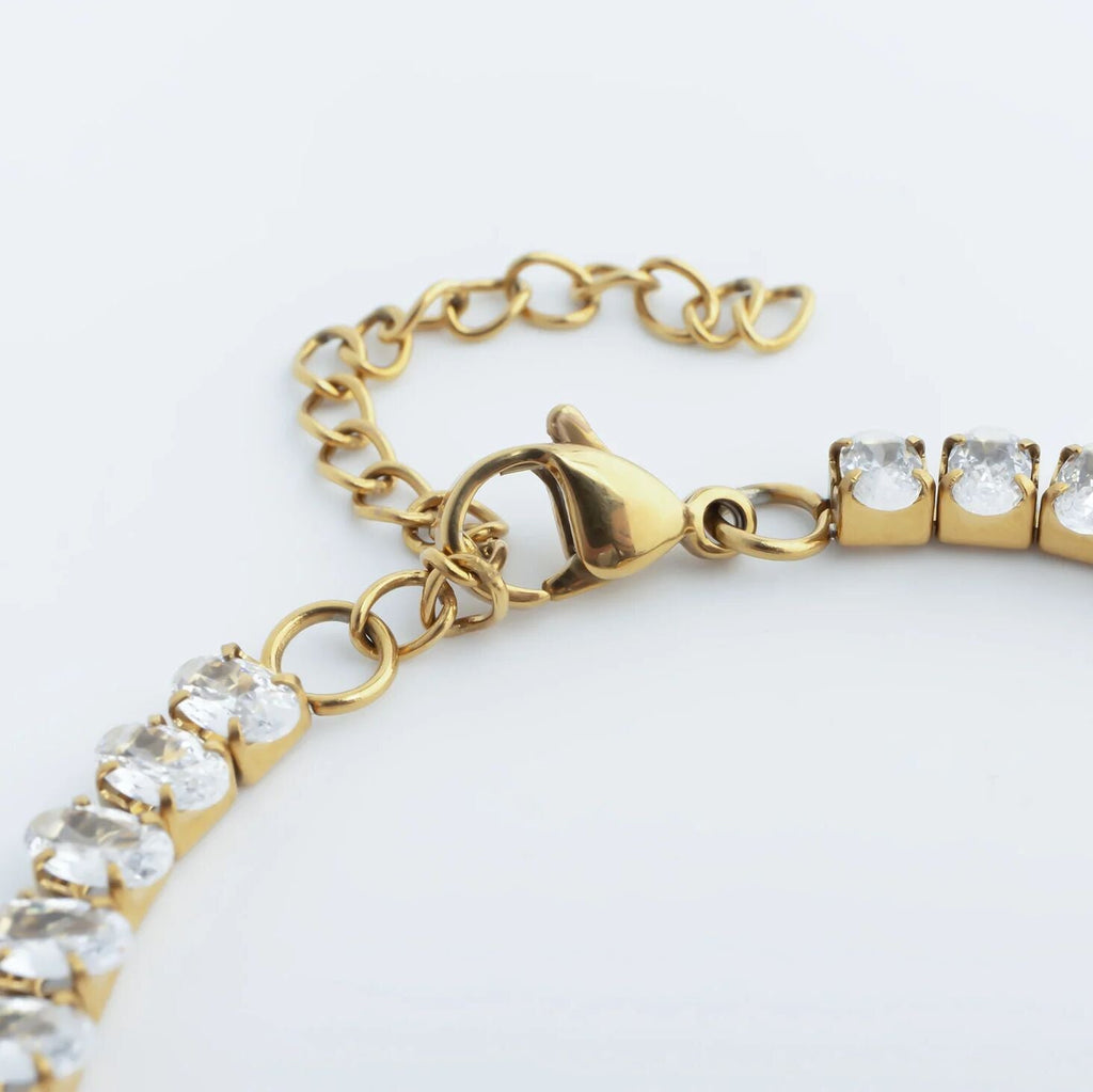 Gold bracelet with clear gemstones on a white background